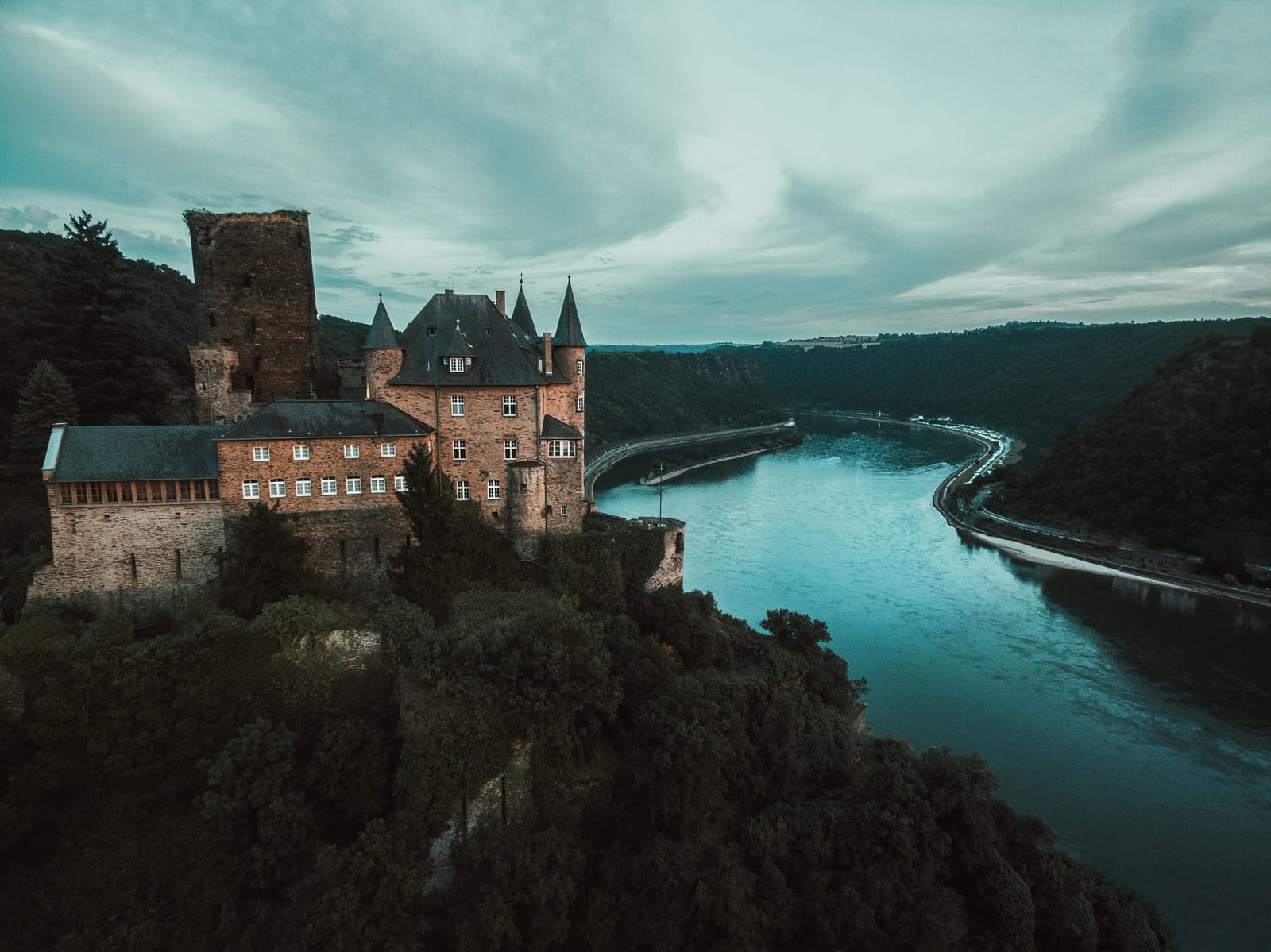 A castle on a rock above a blue-green river