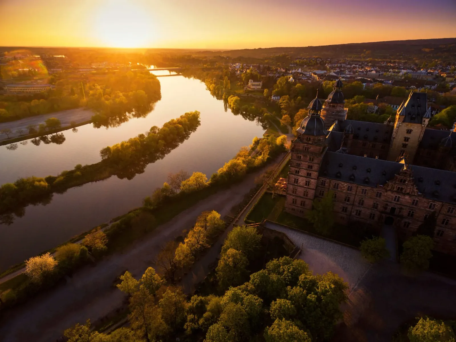A river backlit by the low sun beside a palace