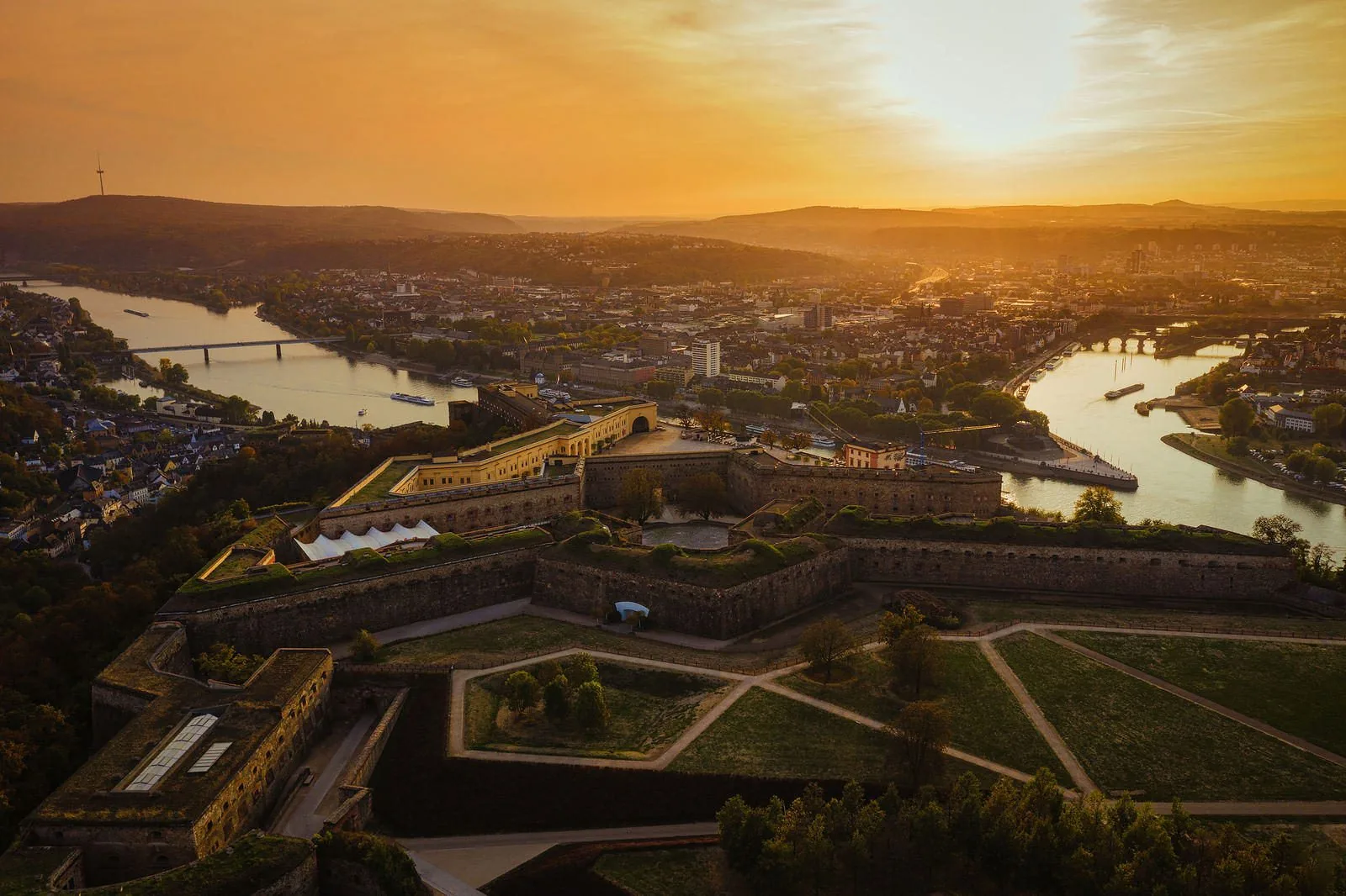 A fortress above two rivers joining in golden light