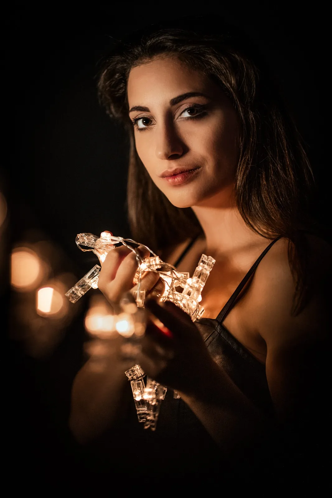 Candlelit portrait with a string of lights in her hands