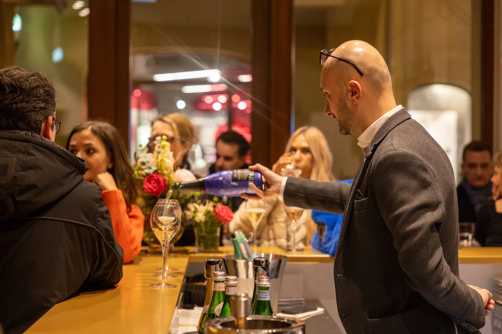 Service schenkt an der Theke ein, Gäste im Gespräch entlang der Bar