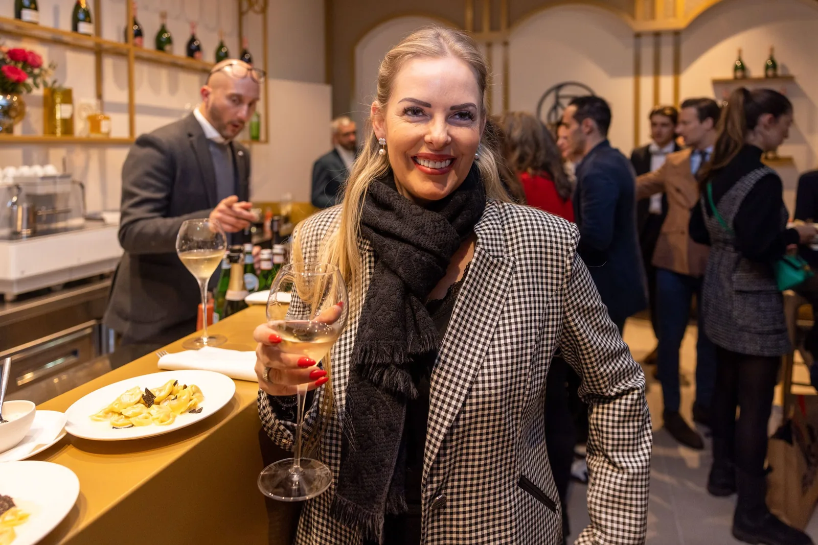 Gast mit einem Glas Champagner an der Theke, daneben ein angerichteter Teller