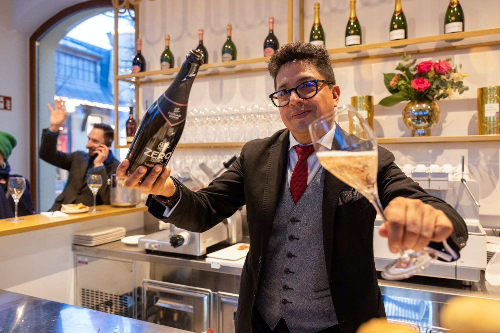 Barkeeper präsentiert Flasche und Glas hinter dem Tresen einer Champagnerbar