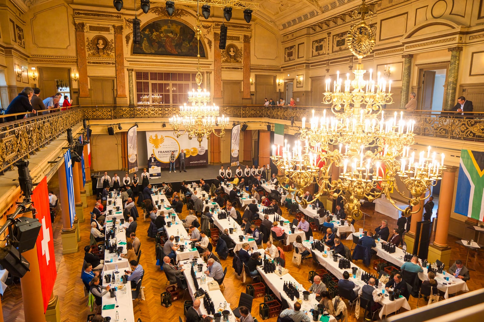 Festsaal mit Kronleuchtern und langen eingedeckten Tafeln während einer Veranstaltung