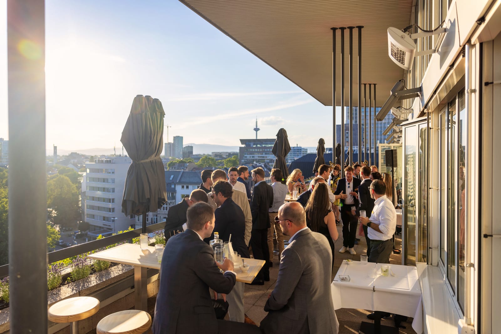 Abendliche Dachterrasse über Frankfurt mit Gästen einer Firmenveranstaltung vor der Skyline