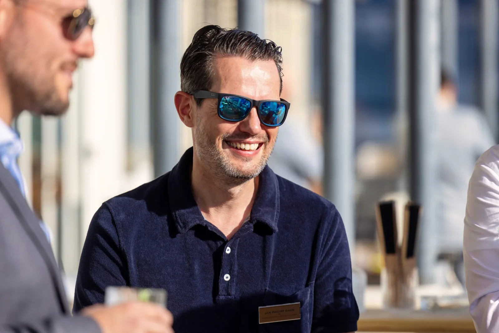 Laughing man in conversation at a corporate event, daylight from the window front
