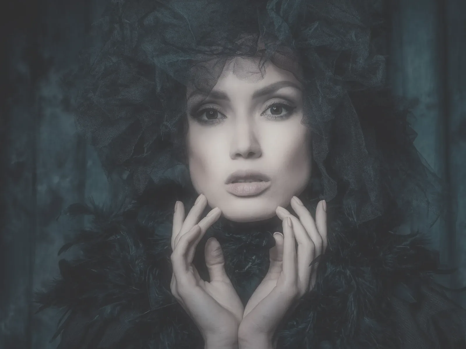 Neutral development: Portrait of a woman in black tulle and feathers, hands at her face, against dark teal