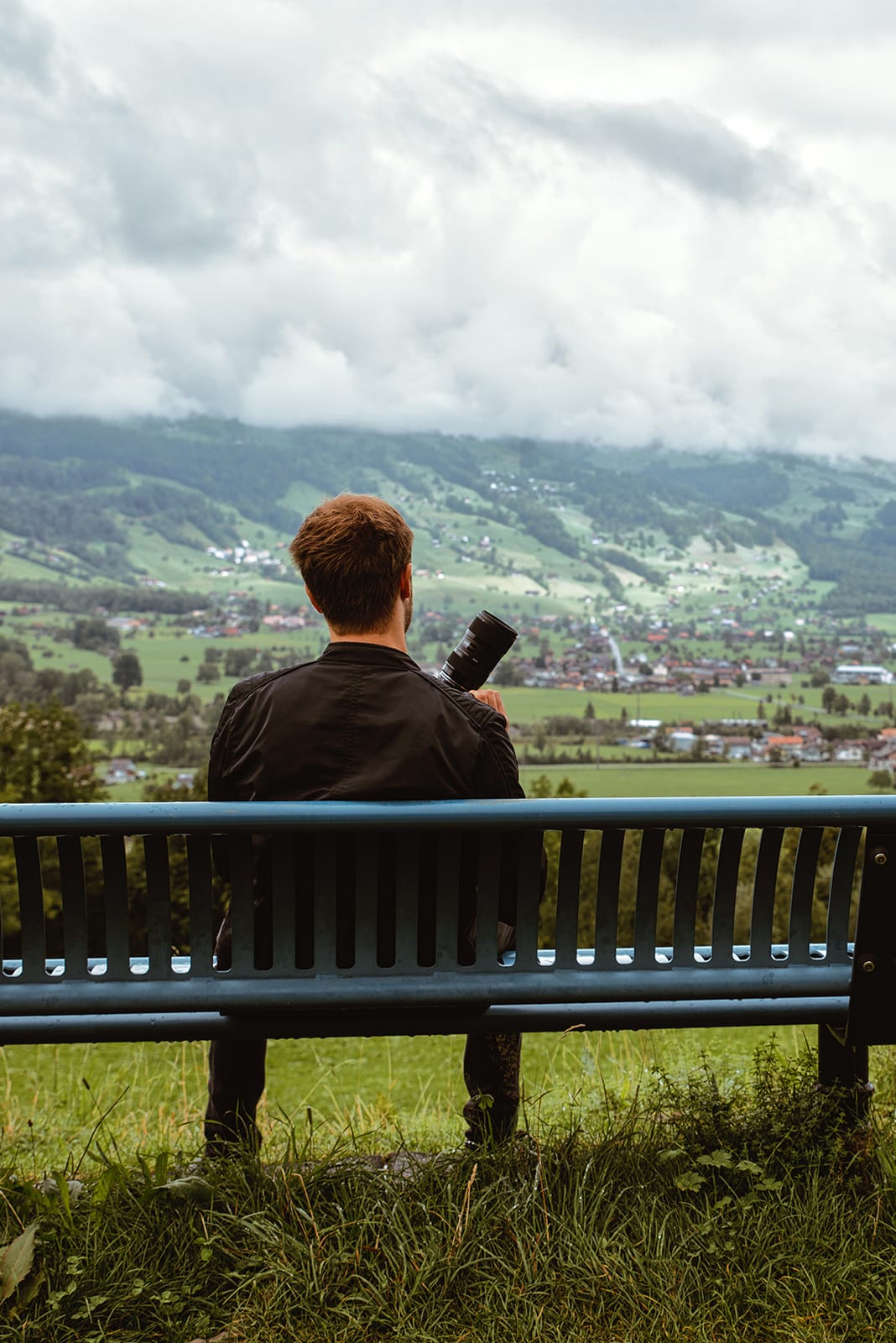 Fotograf mit Kamera auf einer Bank über einem weiten Tal