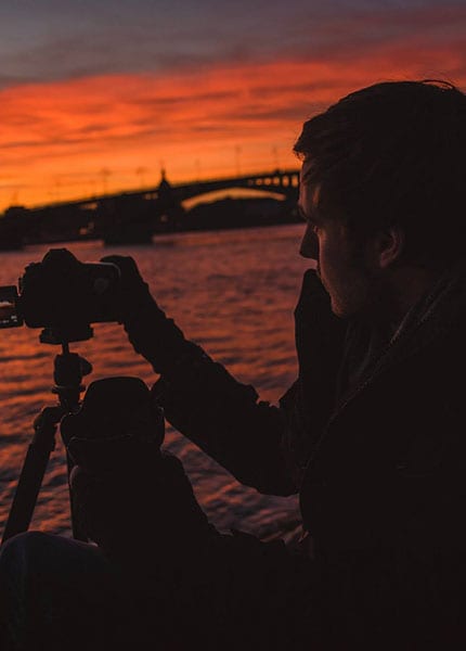 Fotograf mit Kamera auf dem Stativ im Abendrot