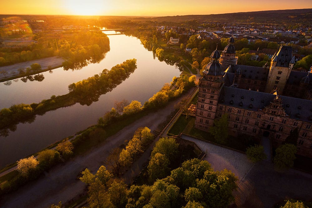 Flusslauf mit Schloss aus der Luft im Abendlicht