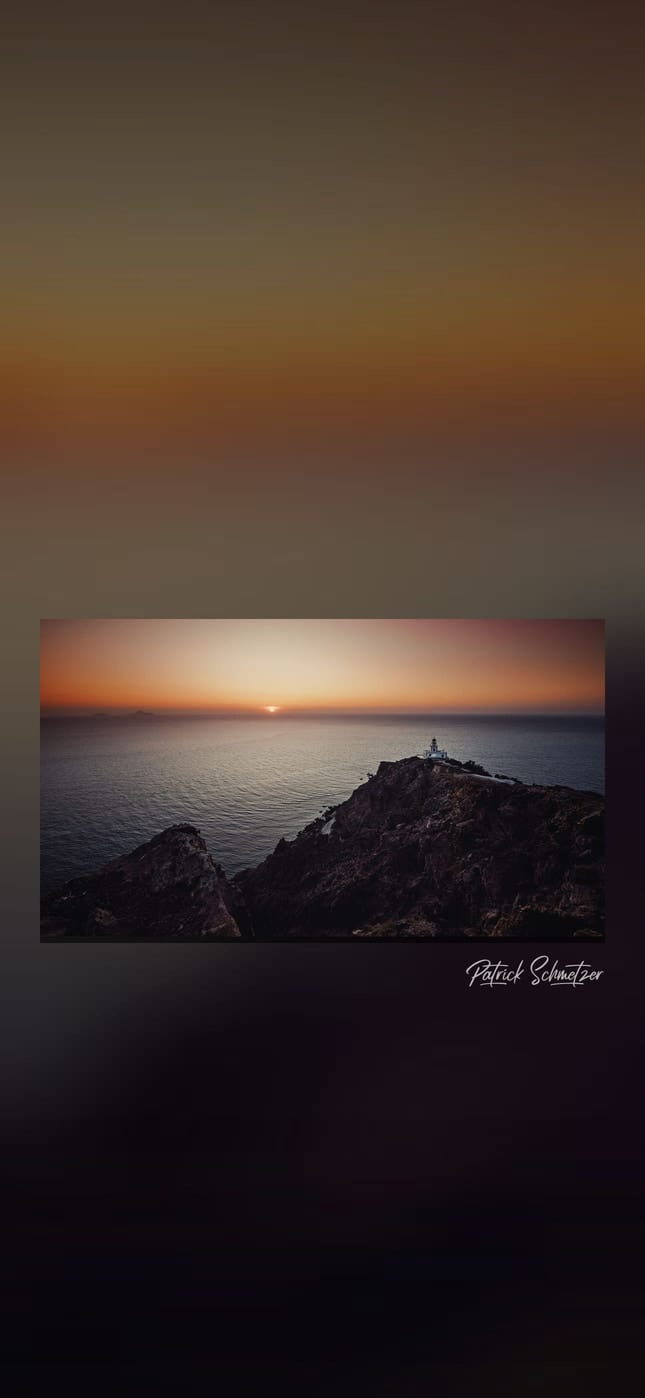 Leuchtturm auf einer Felsküste über dem Meer bei Sonnenuntergang